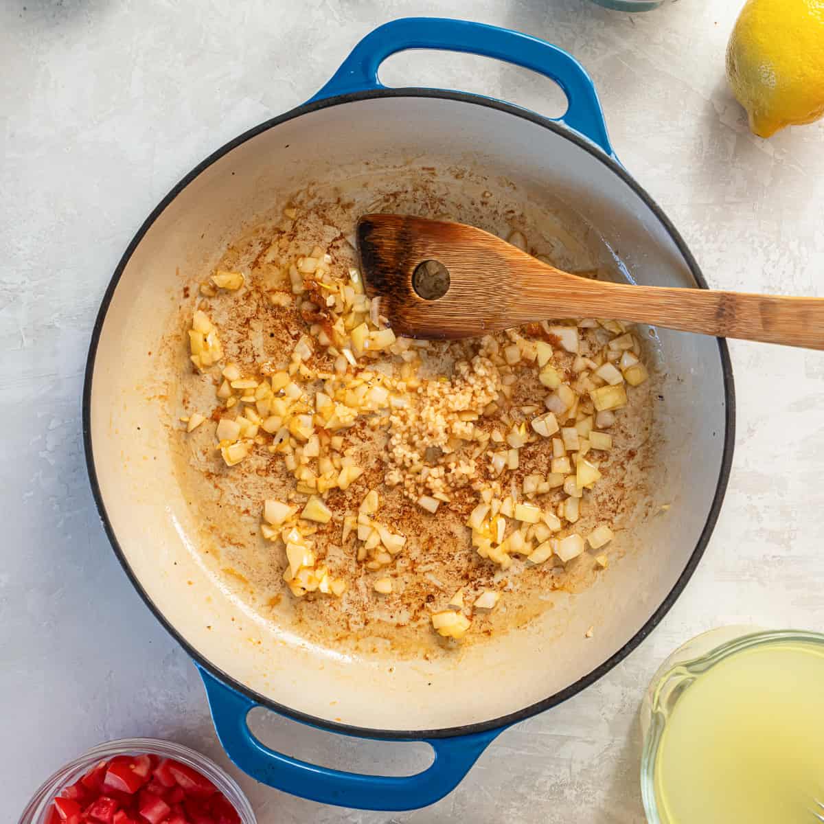 Chopped onion and garlic saut&eacute;ing in a skillet after searing shrimp.