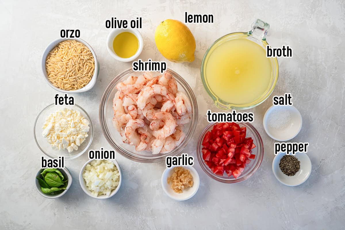 Ingredients for orzo pasta with shrimp including shrimp, orzo, feta cheese, Roma tomatoes, lemon, olive oil, onion, garlic, basil, chicken broth, salt, and pepper.