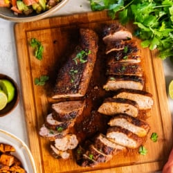 Oven roasted pork tenderloin seasoned with Southwestern spices, sliced and served on a cutting board.