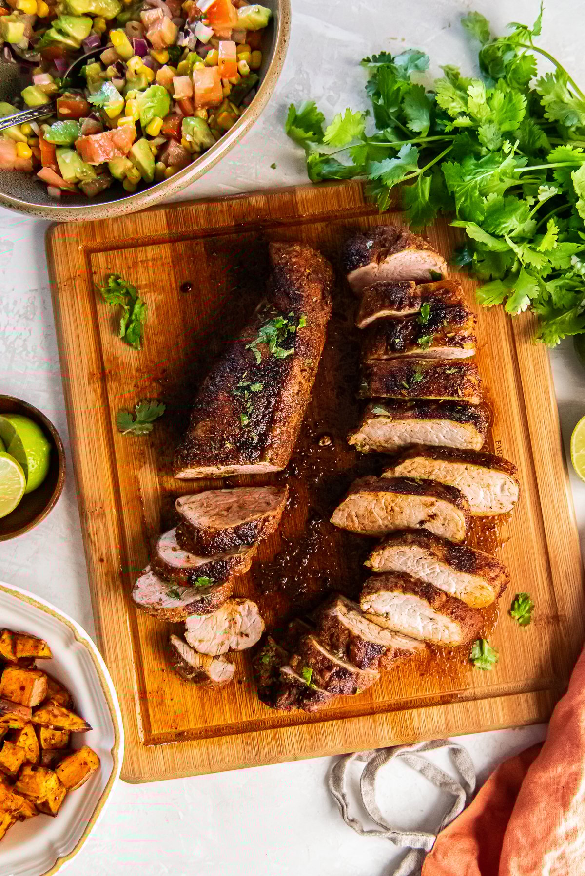 Oven roasted pork tenderloin seasoned with Southwestern spices, sliced and served on a cutting board.