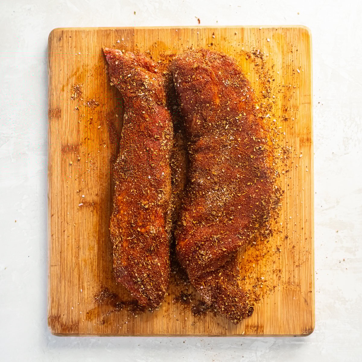Spiced pork tenderloin on a wood cutting board.