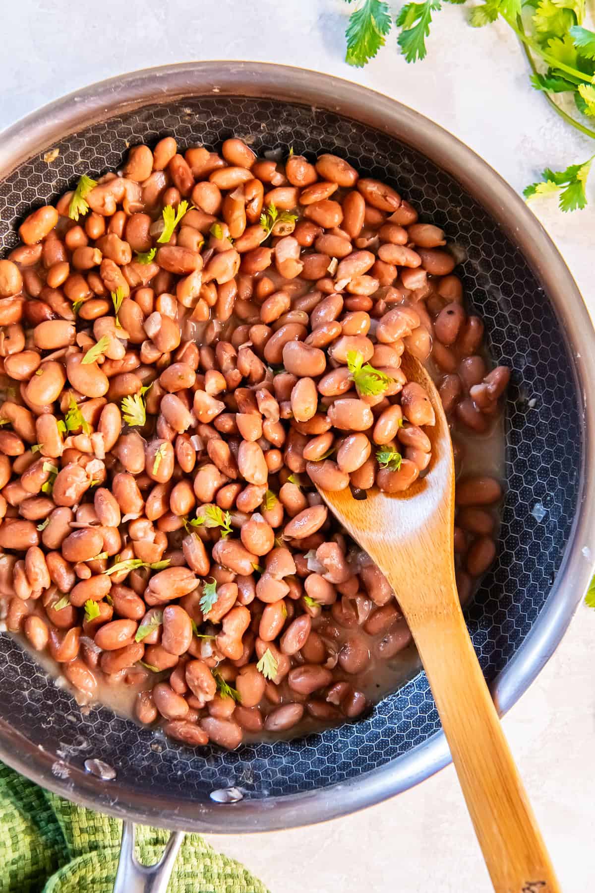 Easy seasoned pinto beans in a skillet with a wooden spoon