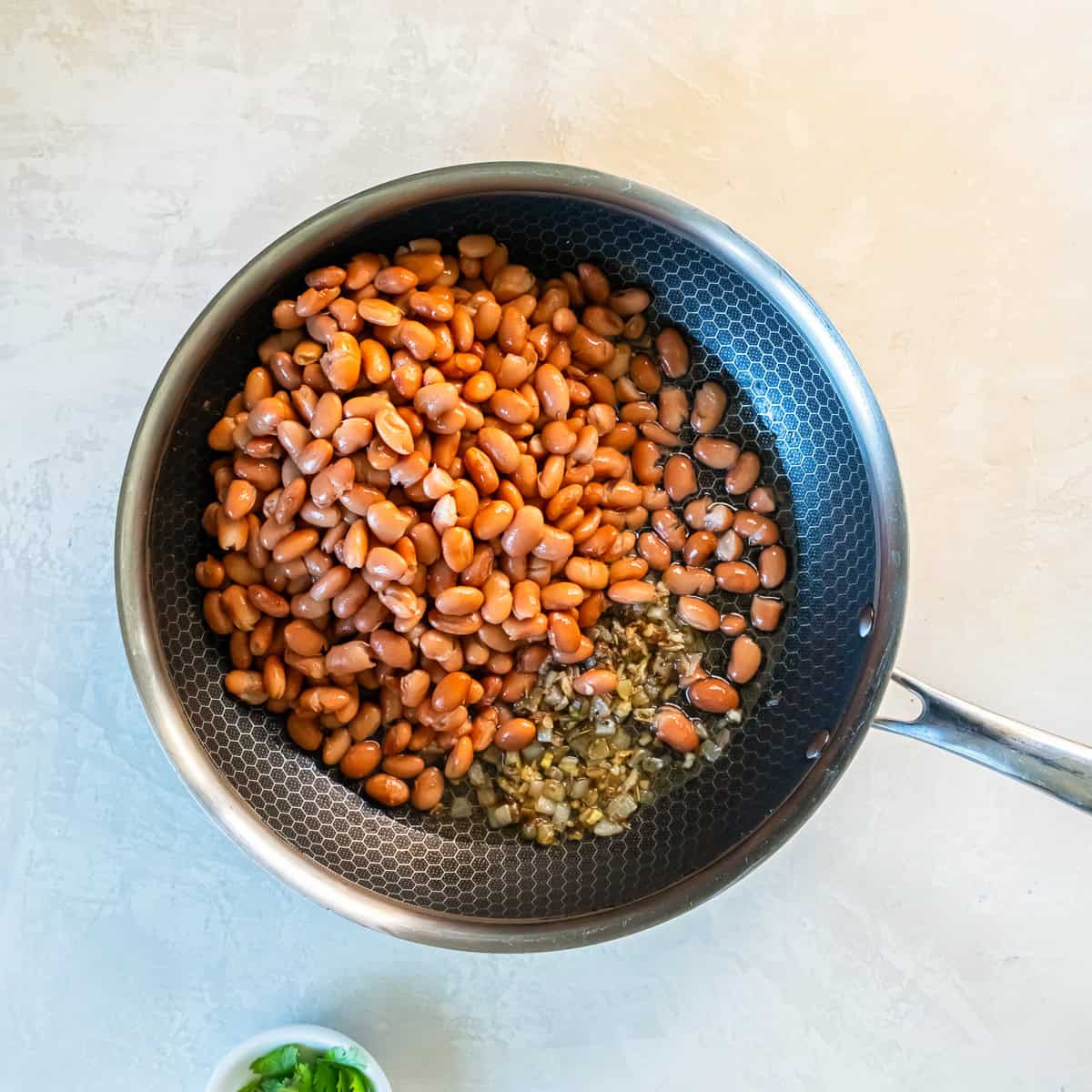 Canned pinto beans added to the skillet with sautéed onion and garlic