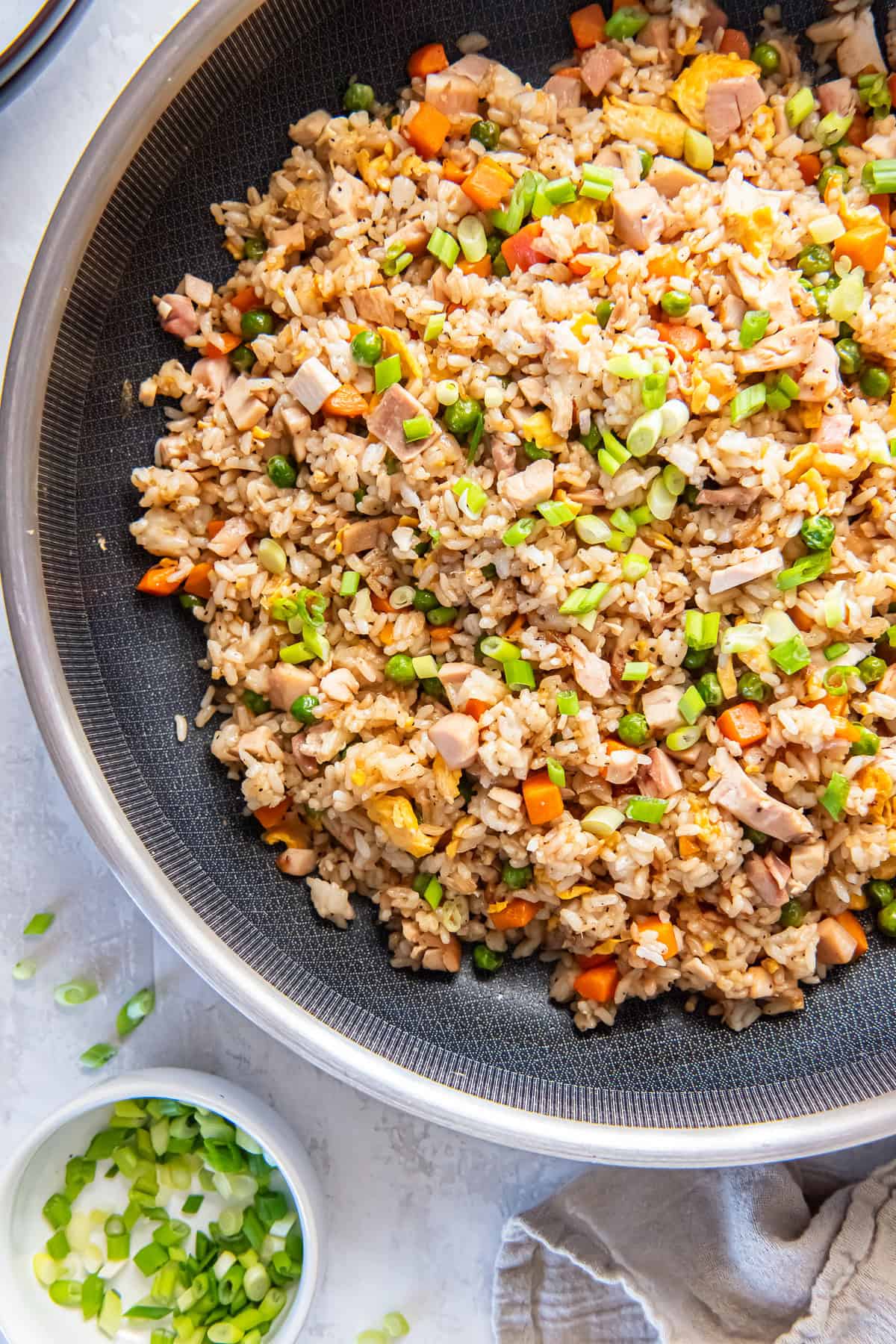 Chicken fried rice in a skillet with vegetables, scrambled eggs, chopped chicken, and green onions.