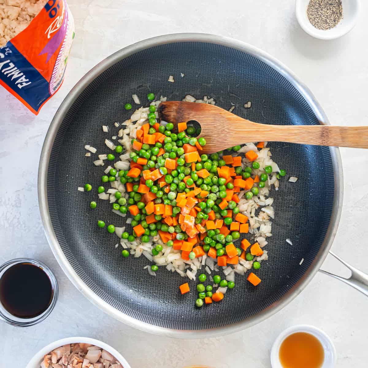 Frozen peas and carrots added to saut&eacute;ed onion in a skillet.