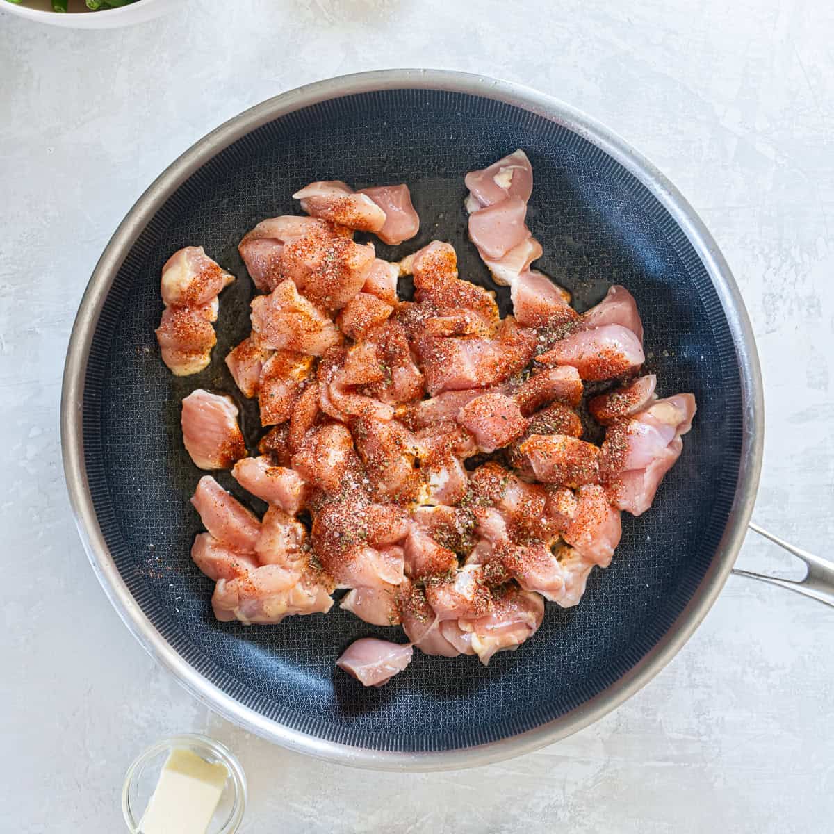 Seasoned chicken in a skillet.