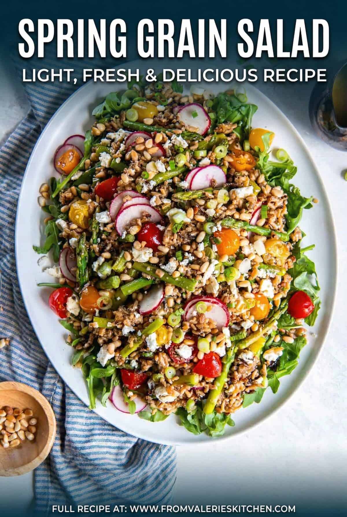 Spring grain salad with asparagus, radishes, cherry tomatoes, goat cheese, pine nuts, and arugula tossed in apple cider vinaigrette on a serving platter with title text overlay.