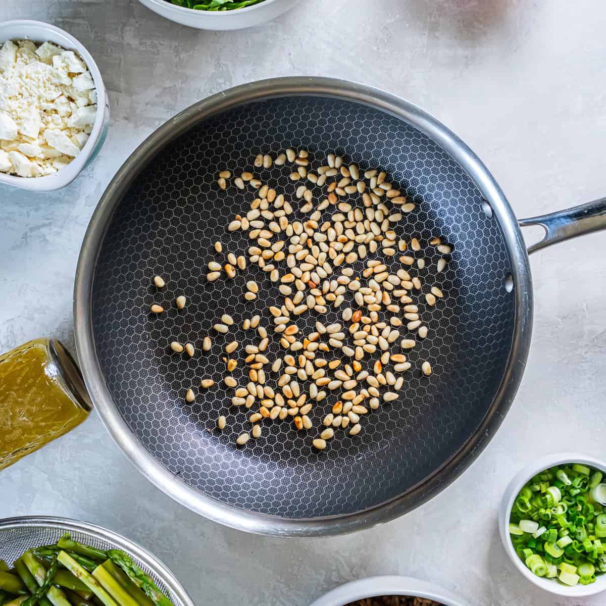 Toasting pine nuts in a skillet until lightly golden.