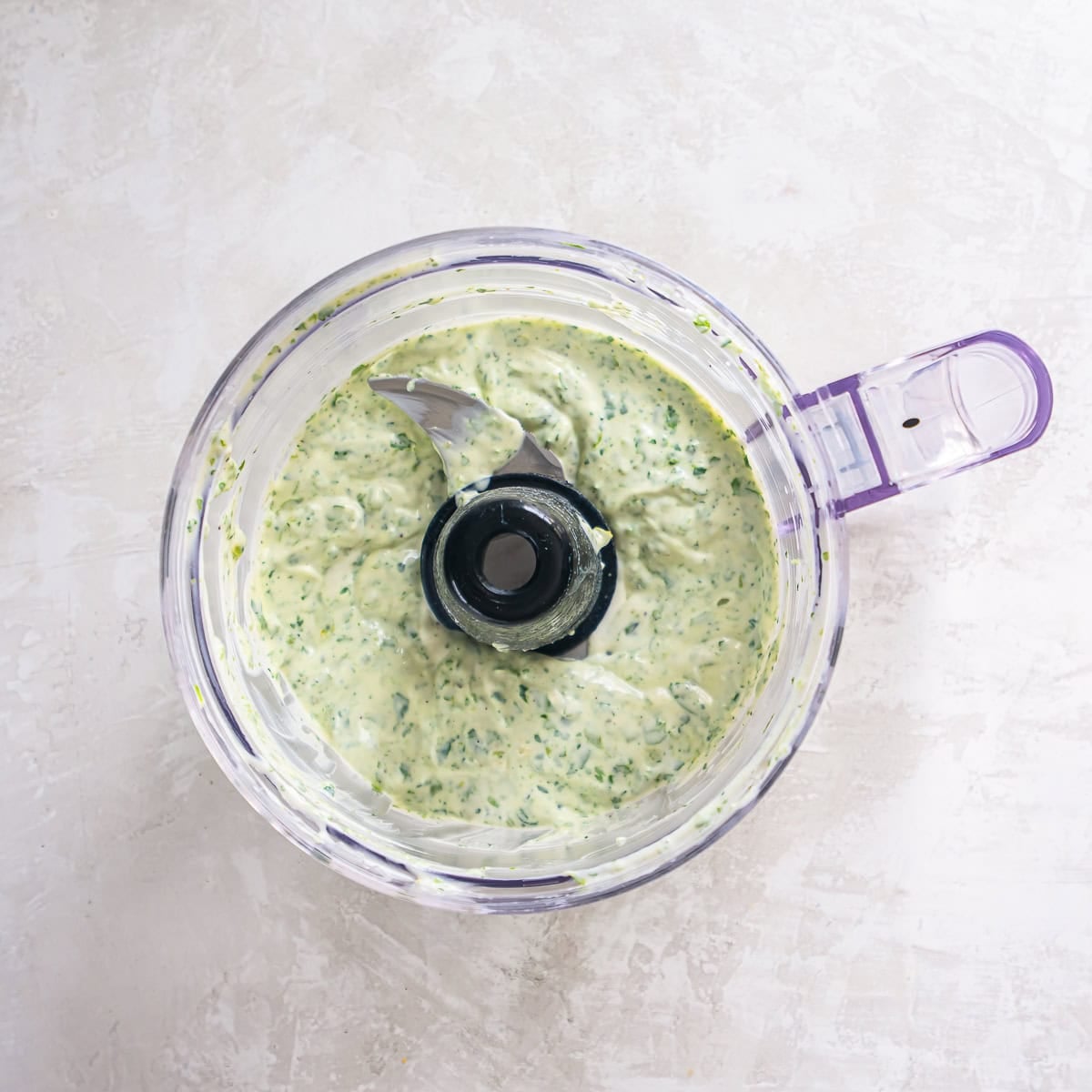 Cilantro lime sauce blended smooth in a food processor with a creamy green texture.