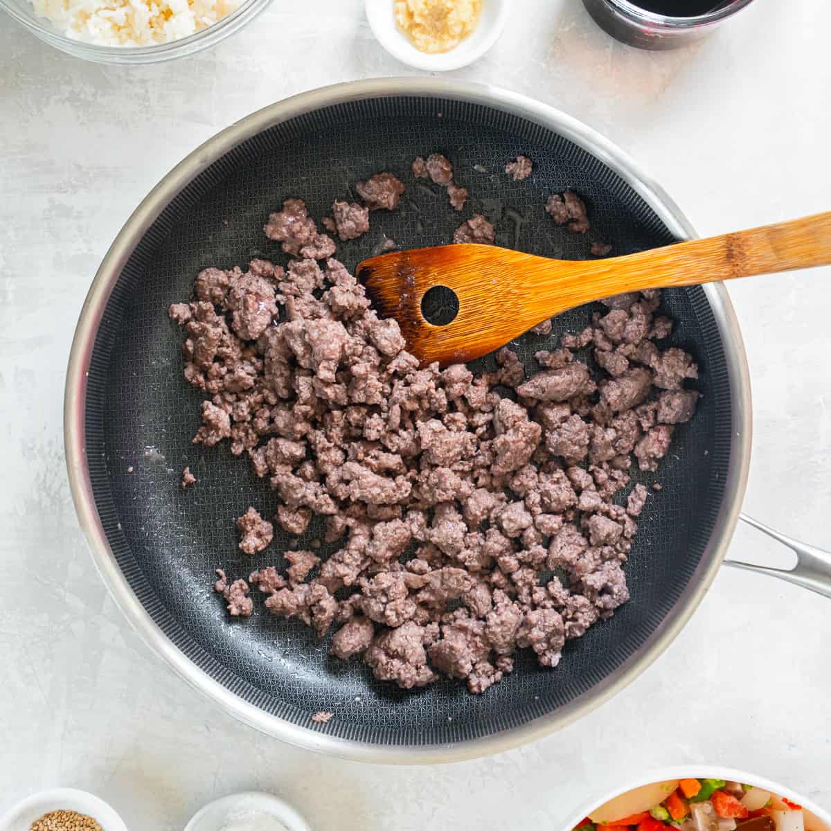Ground beef cooking in a skillet for teriyaki beef bowls.