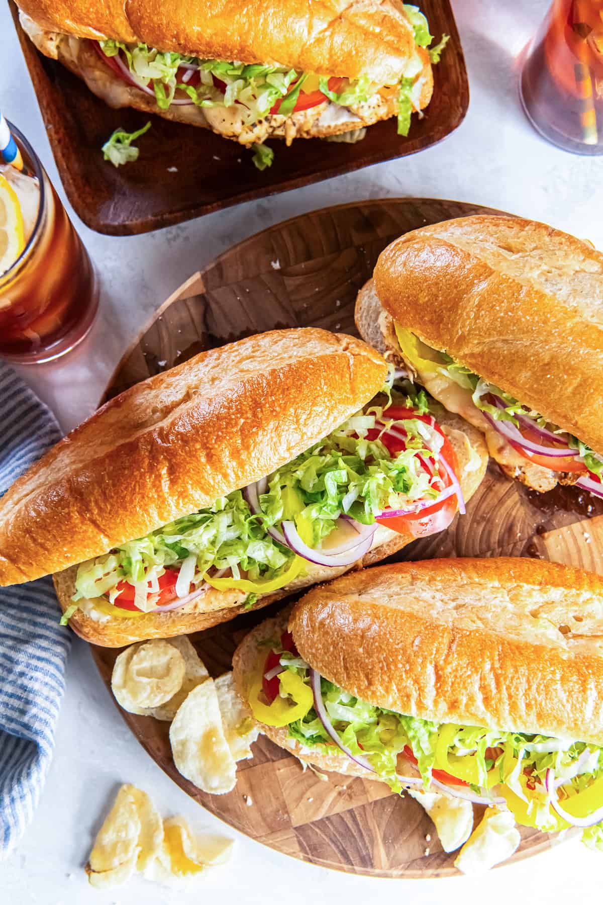 Italian chicken sub sandwiches on sandwich rolls served with chips and iced tea.
