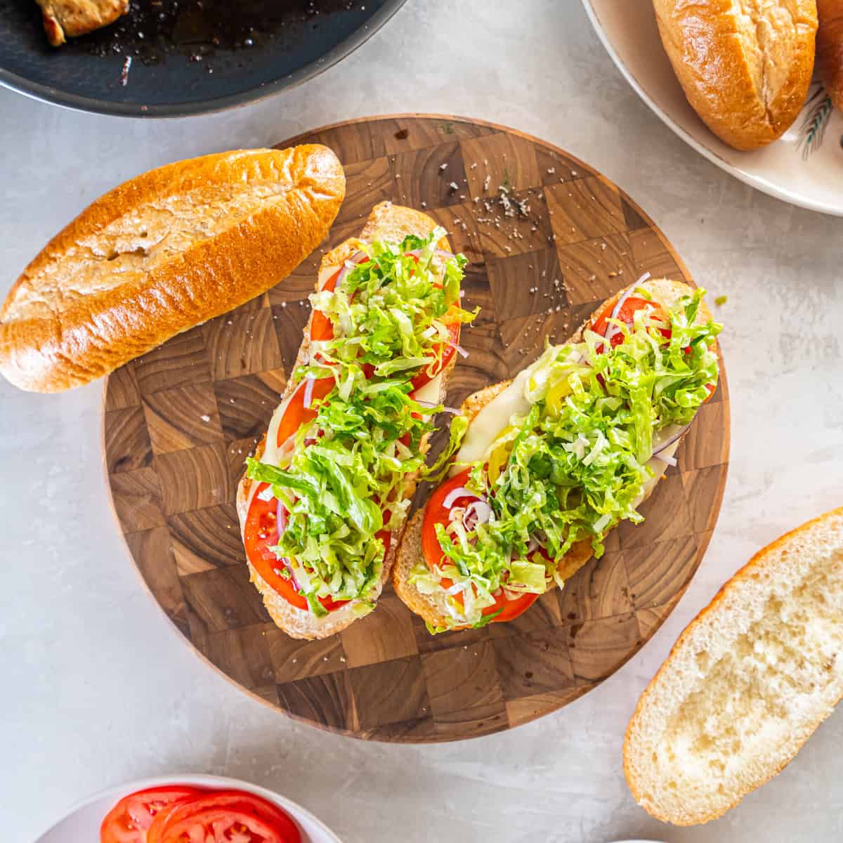 Topping sandwiches with shredded lettuce before closing.