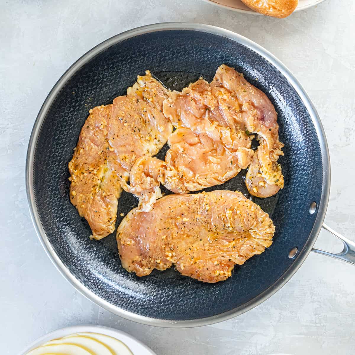 Chicken breasts cooking in a skillet.