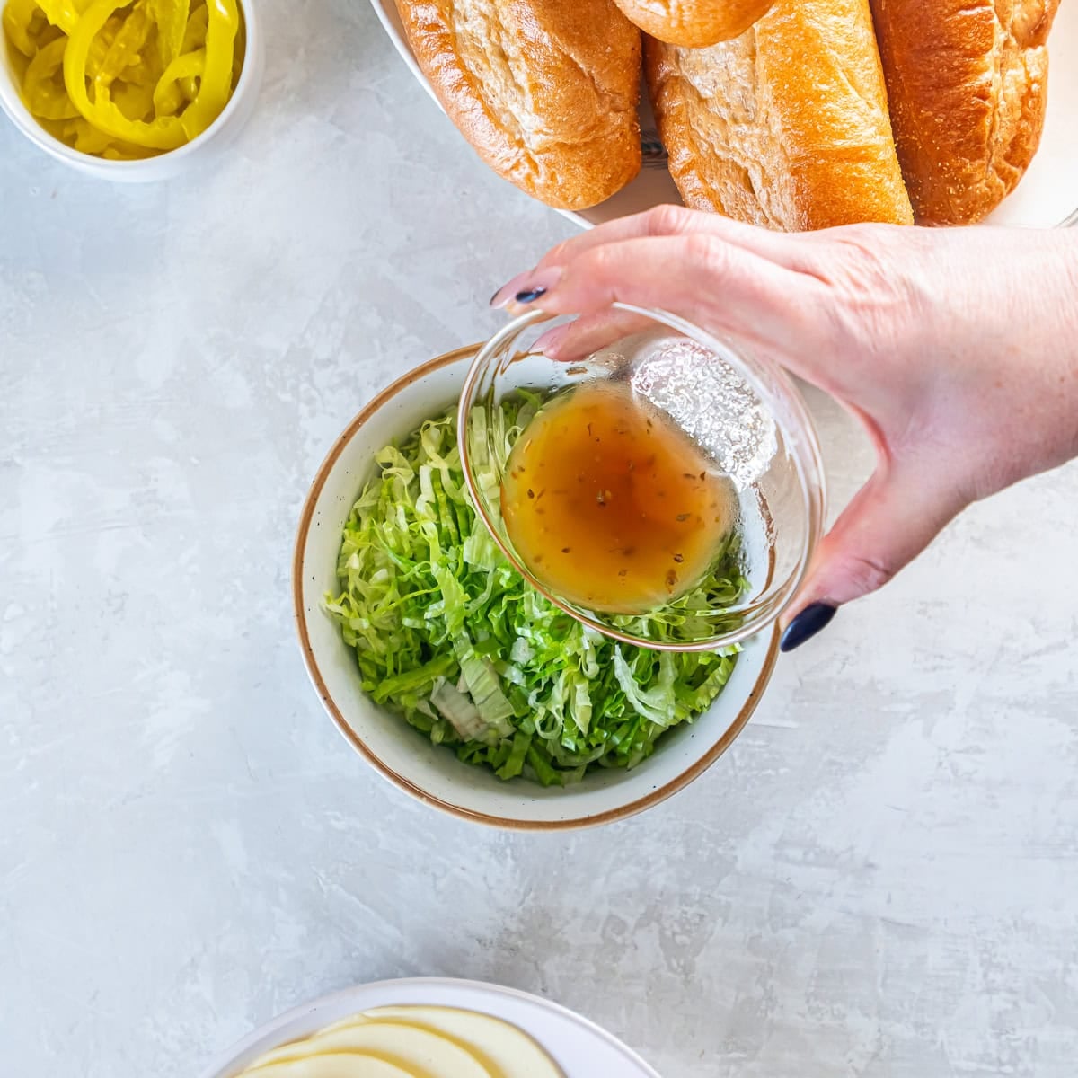 Pouring oil and vinegar dressing over shredded iceberg lettuce.