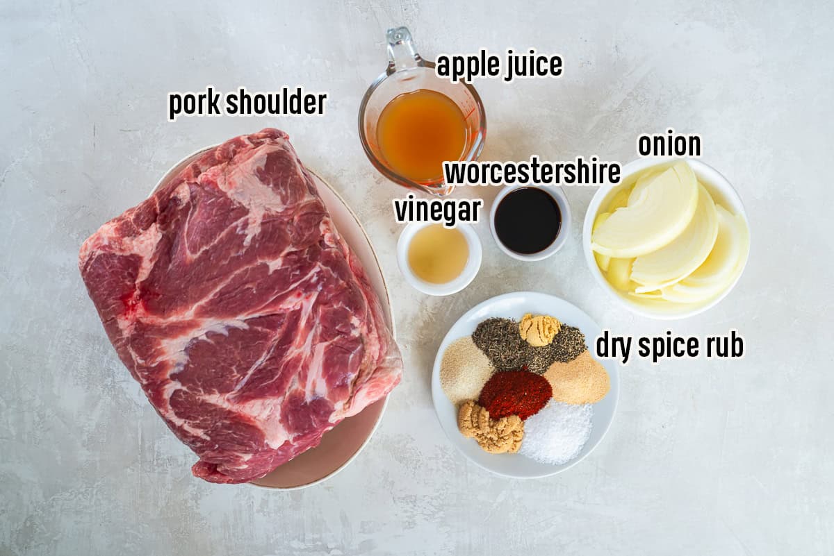 Alt text:
Ingredients for slow cooker pulled pork including pork shoulder, sliced onion, apple juice, Worcestershire sauce, vinegar, and dry spice rub.