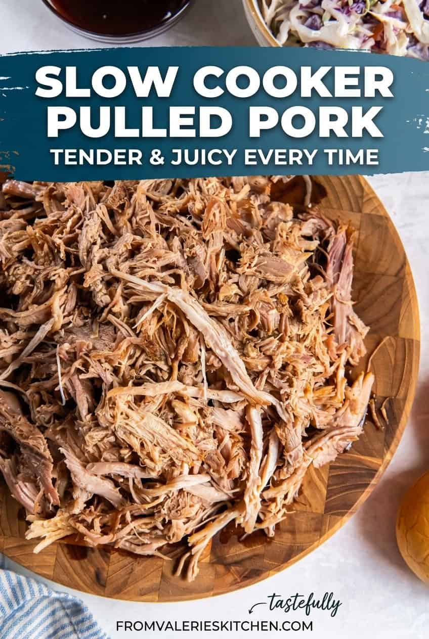Slow cooker pulled pork shredded and piled on a wooden board with barbecue sauce and coleslaw in the background with text overlay.
