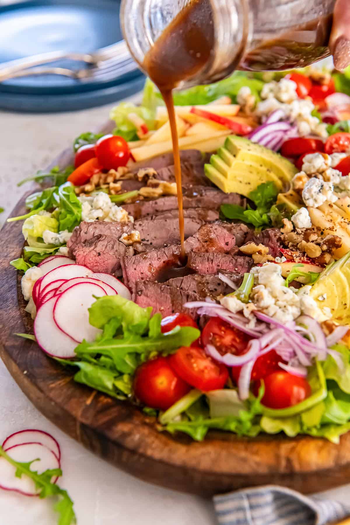 Pour balsamic vinaigrette over steak salad with sliced sirloin, apples, avocado, and blue cheese.