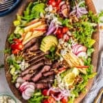 Steak salad with sliced sirloin, apple, avocado, blue cheese, and walnuts on a bed of romaine and arugula