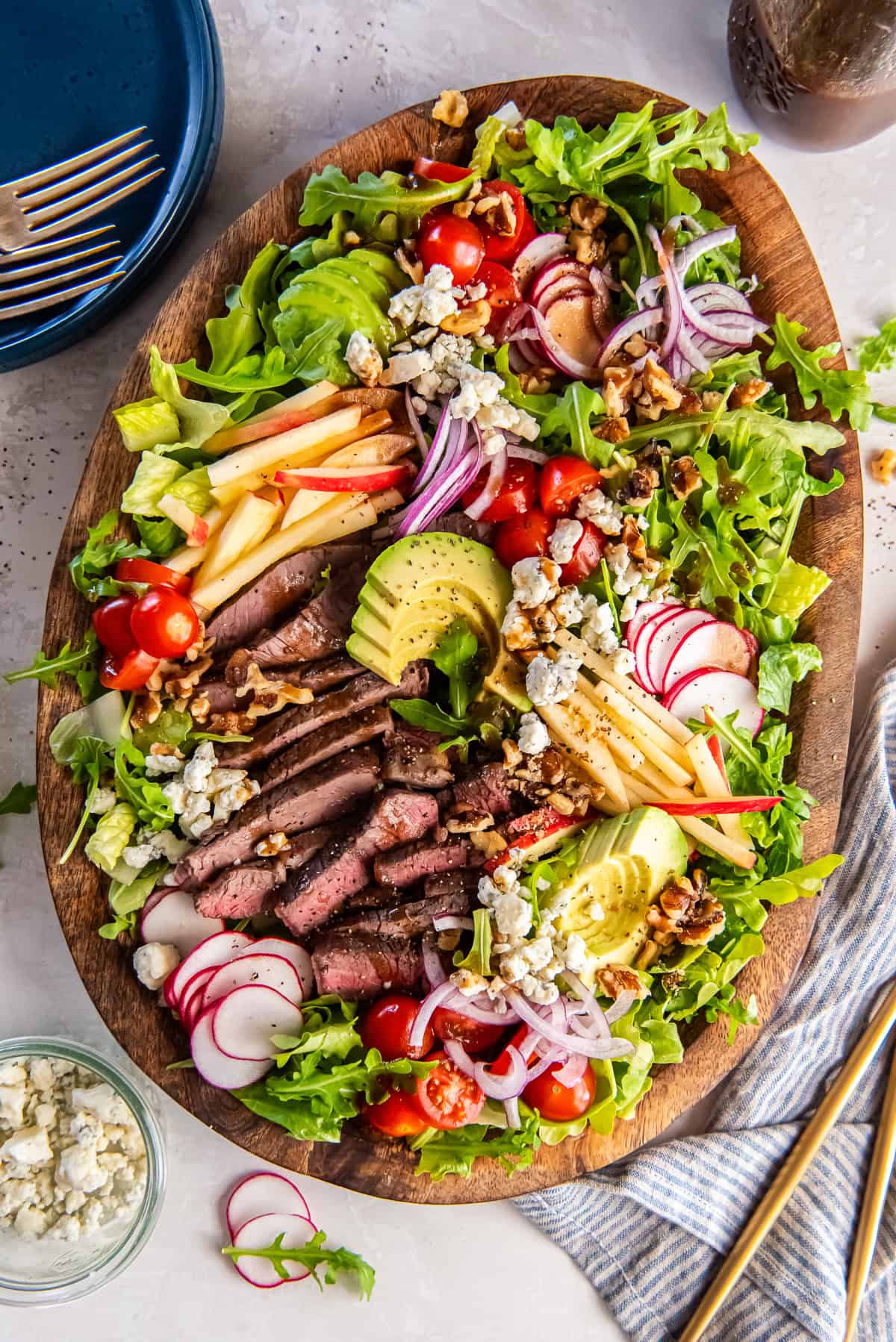 Steak salad with sliced sirloin, apple, avocado, blue cheese and walnuts on a bed of romaine and arugula