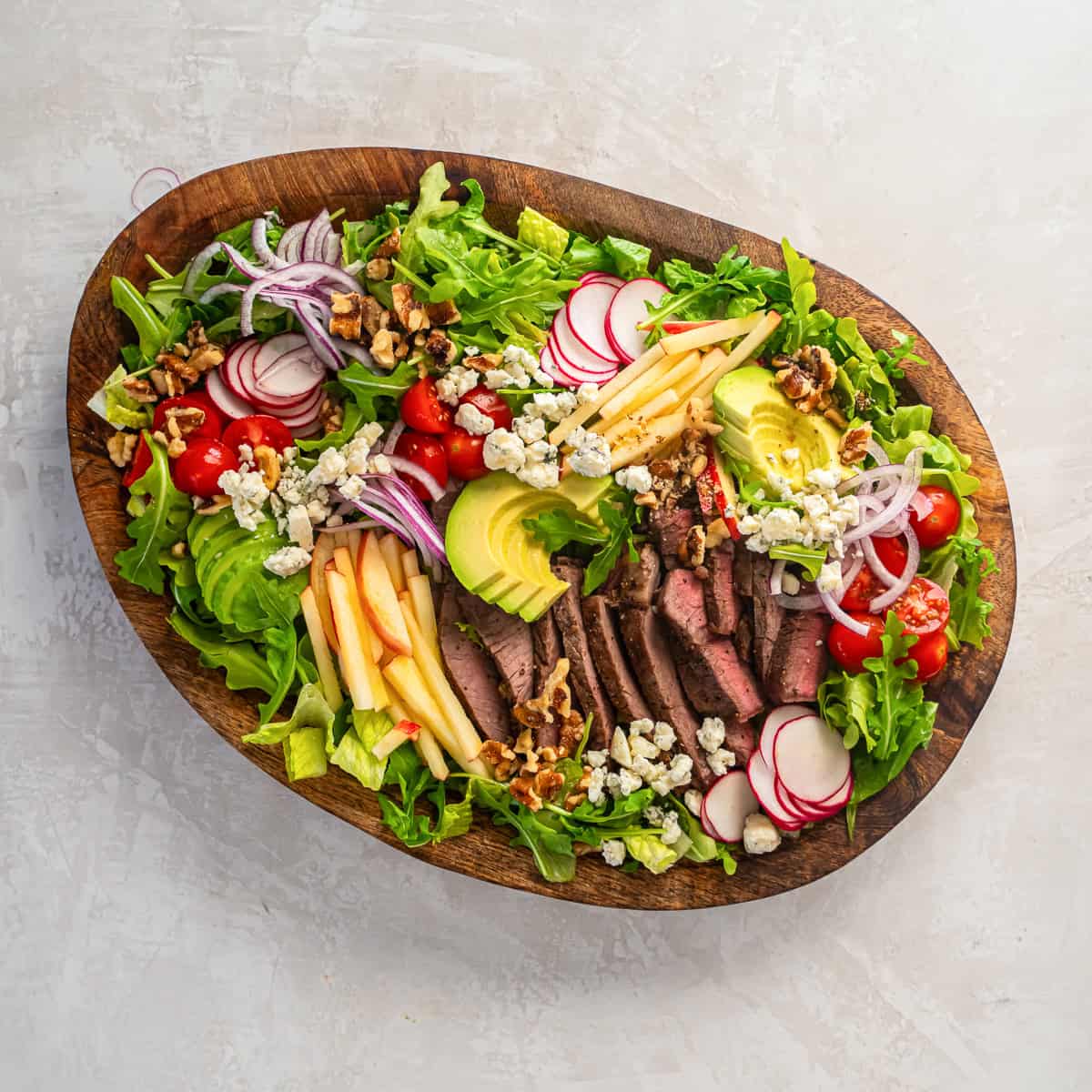 Steak salad with tomatoes, red onions, blue cheese, and walnuts.