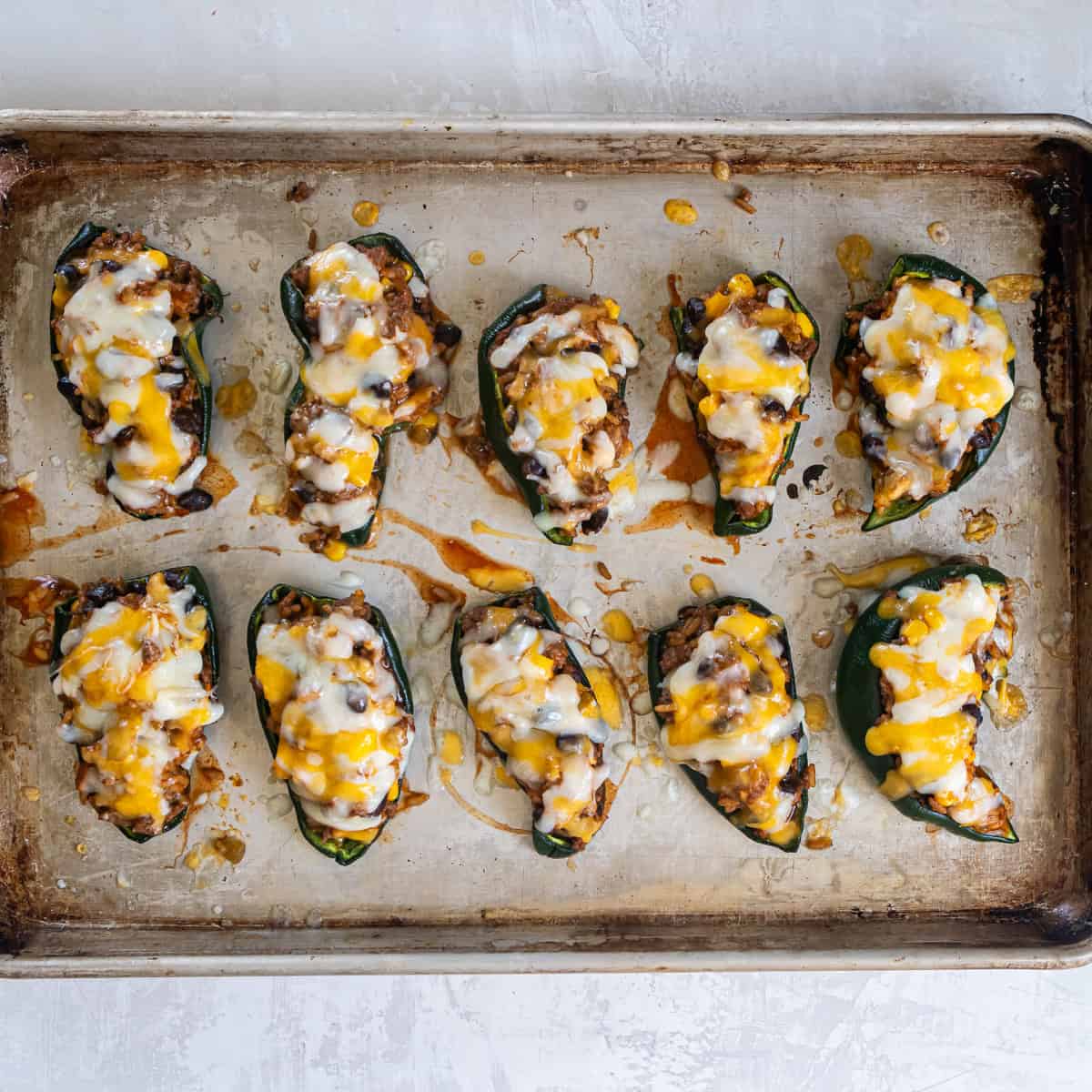 Baked stuffed poblano peppers with melted cheese on top.