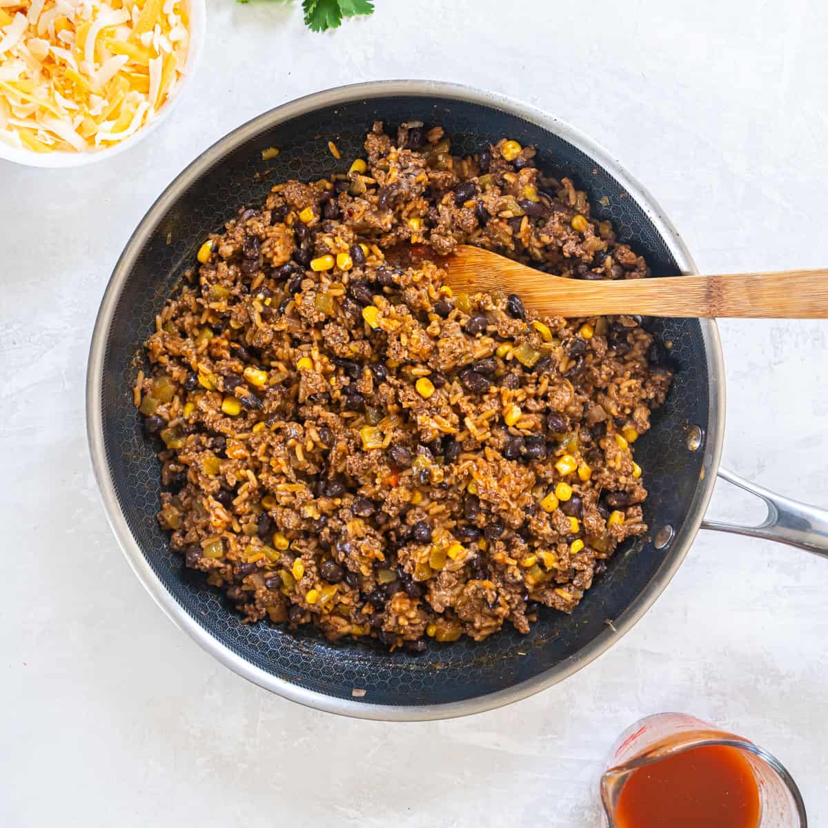 Beef, rice, and bean filling mixed together in a skillet for stuffed peppers.