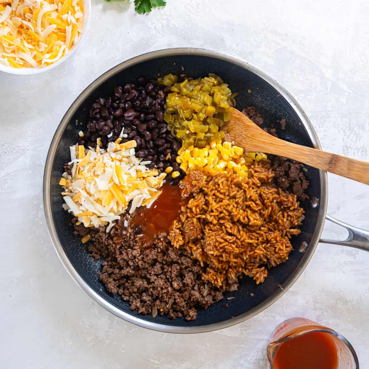Cooked beef with black beans, corn, green chiles, rice, enchilada sauce, and cheese added to the skillet.