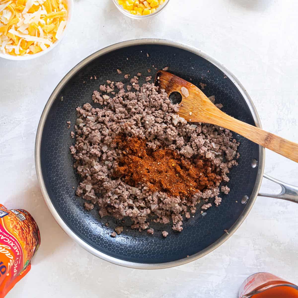 Ground beef cooking with onion and taco seasoning in a skillet.