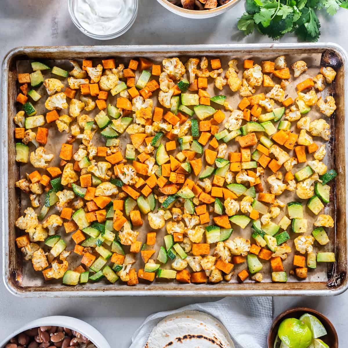 Roasted sweet potato, cauliflower, and zucchini on a sheet pan for chicken and roasted veggie tacos.