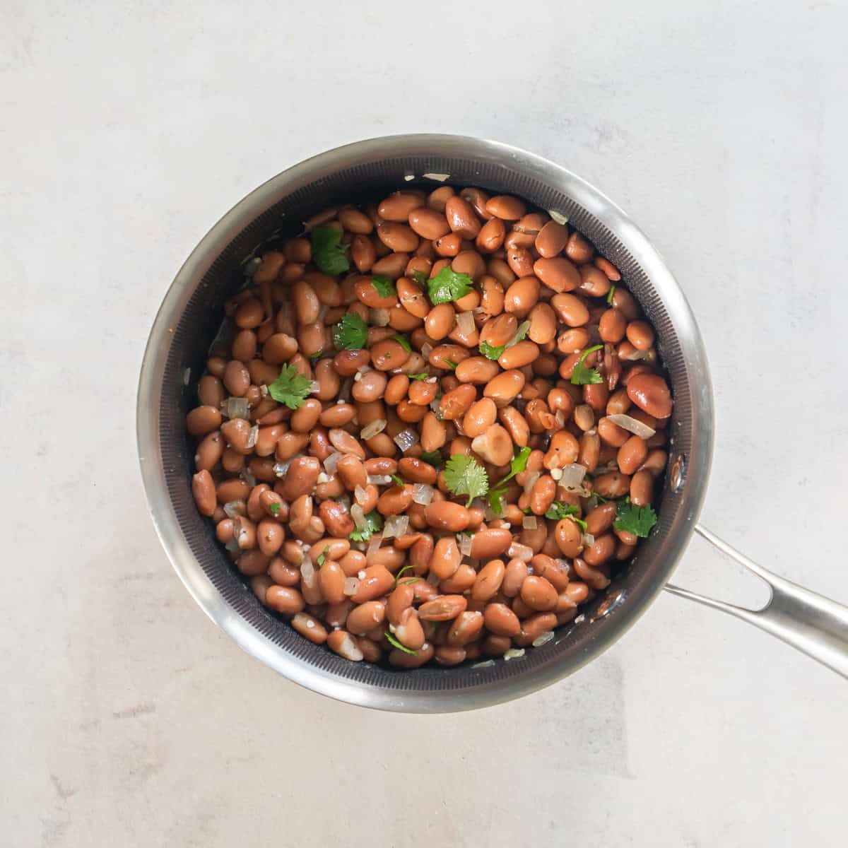 Easy seasoned pinto beans in a small saucepan for chicken and roasted veggie tacos.