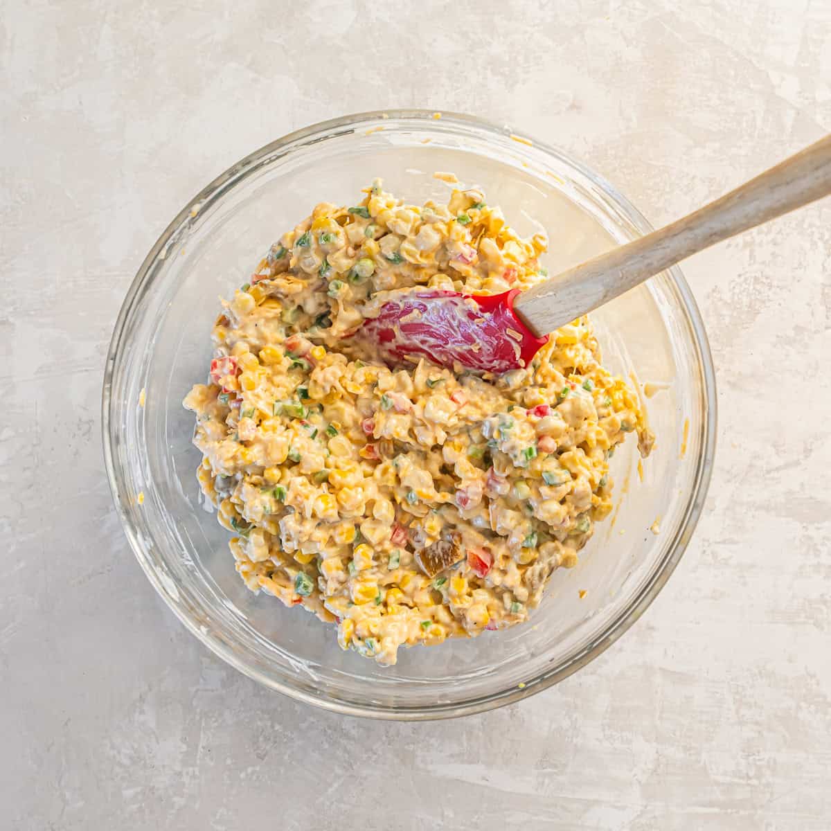 Creamy cold corn dip mixed together in a glass bowl before chilling.