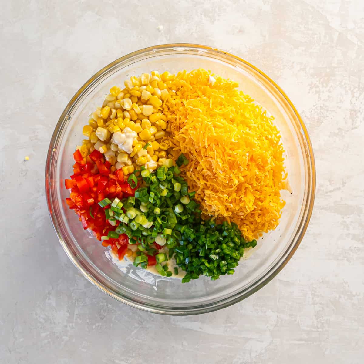 Corn, shredded cheese, diced bell pepper, green onions, and jalapeño added to the cold corn dip mixture.