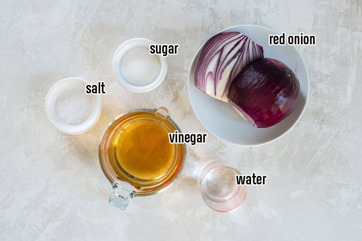 Ingredients for quick pickled red onions including red onion, vinegar, water, sugar, and salt.
