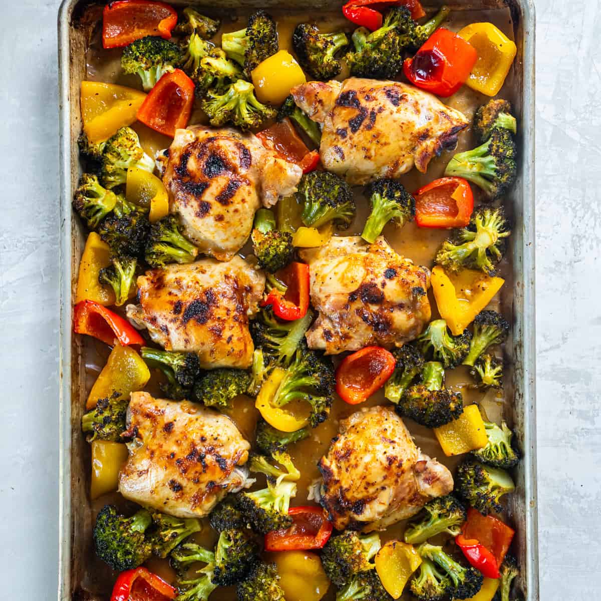 Sheet Pan Honey Mustard Chicken with roasted broccoli and bell peppers on a sheet pan after cooking.
