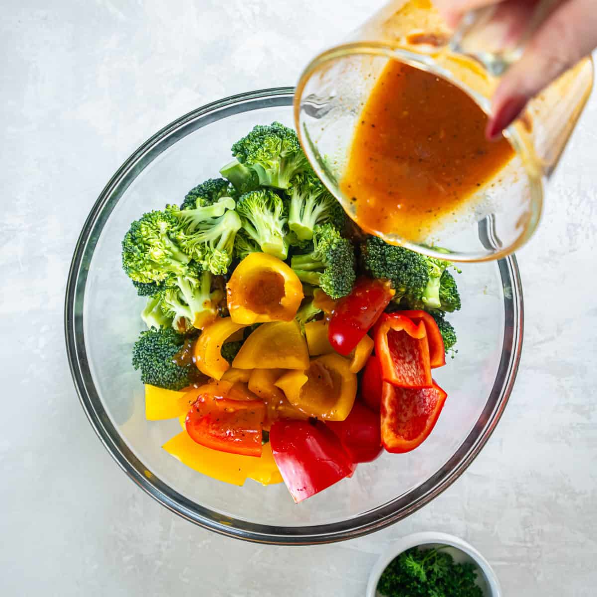 Broccoli and bell peppers tossed with honey mustard sauce in a glass mixing bowl.