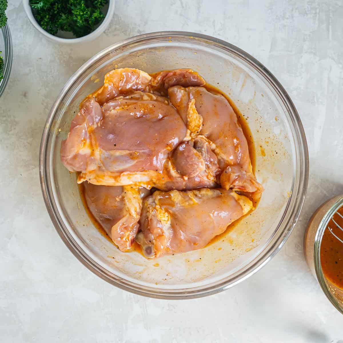 Bone-in chicken thighs coated in honey mustard sauce in a glass mixing bowl.