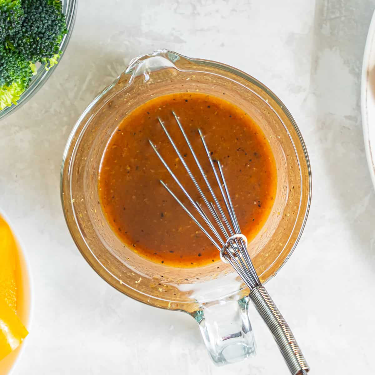 Honey mustard sauce for Sheet Pan Honey Mustard Chicken whisked together in a glass measuring cup.