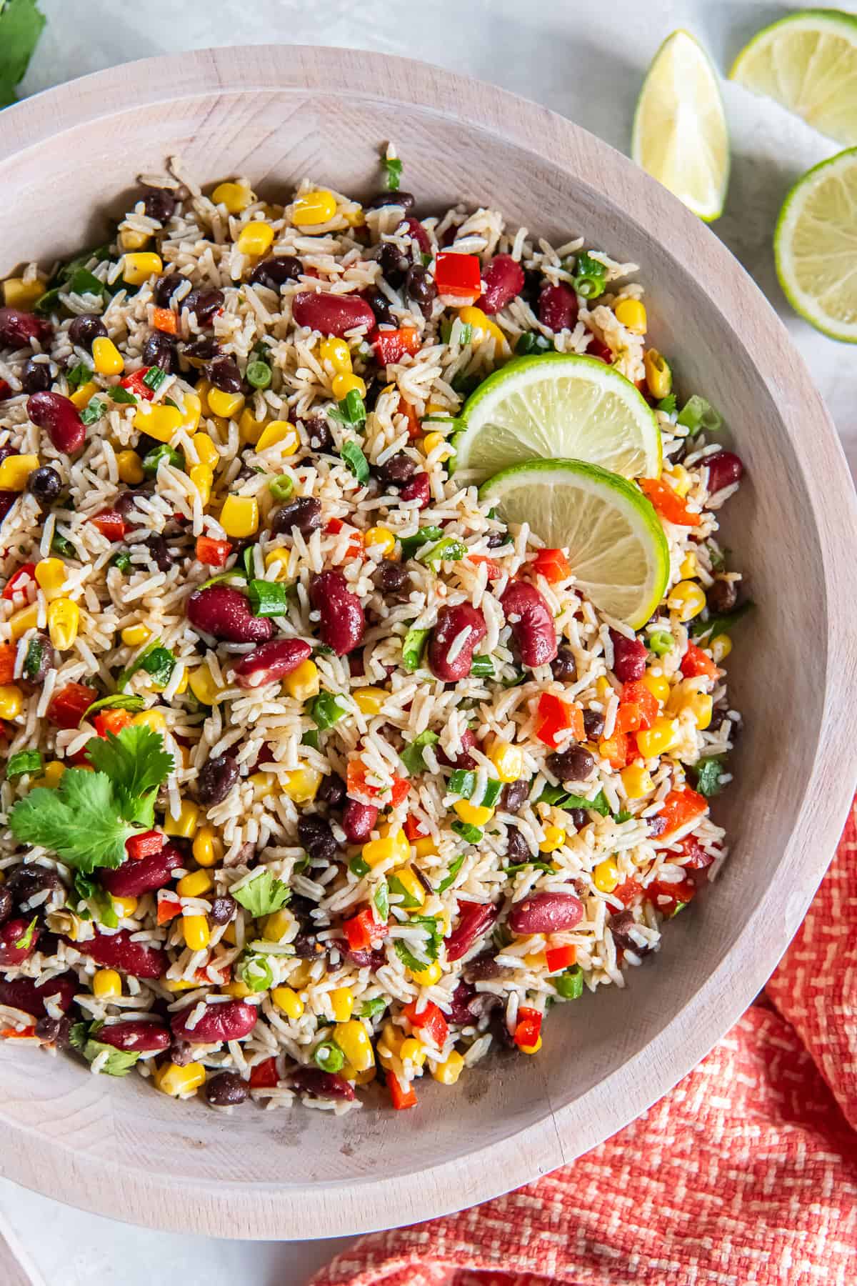 Tex-Mex Rice and Bean Salad with basmati rice, black beans, kidney beans, corn, red bell pepper, and green onions in a wooden bowl.