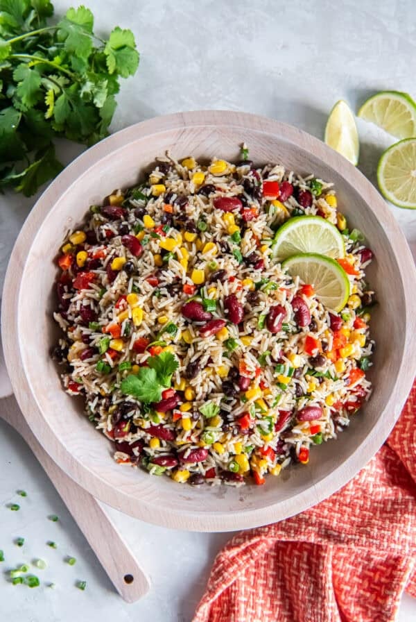Tex-Mex Rice and Bean Salad with basmati rice, black beans, kidney beans, corn, red bell pepper, and green onions in a wooden bowl.