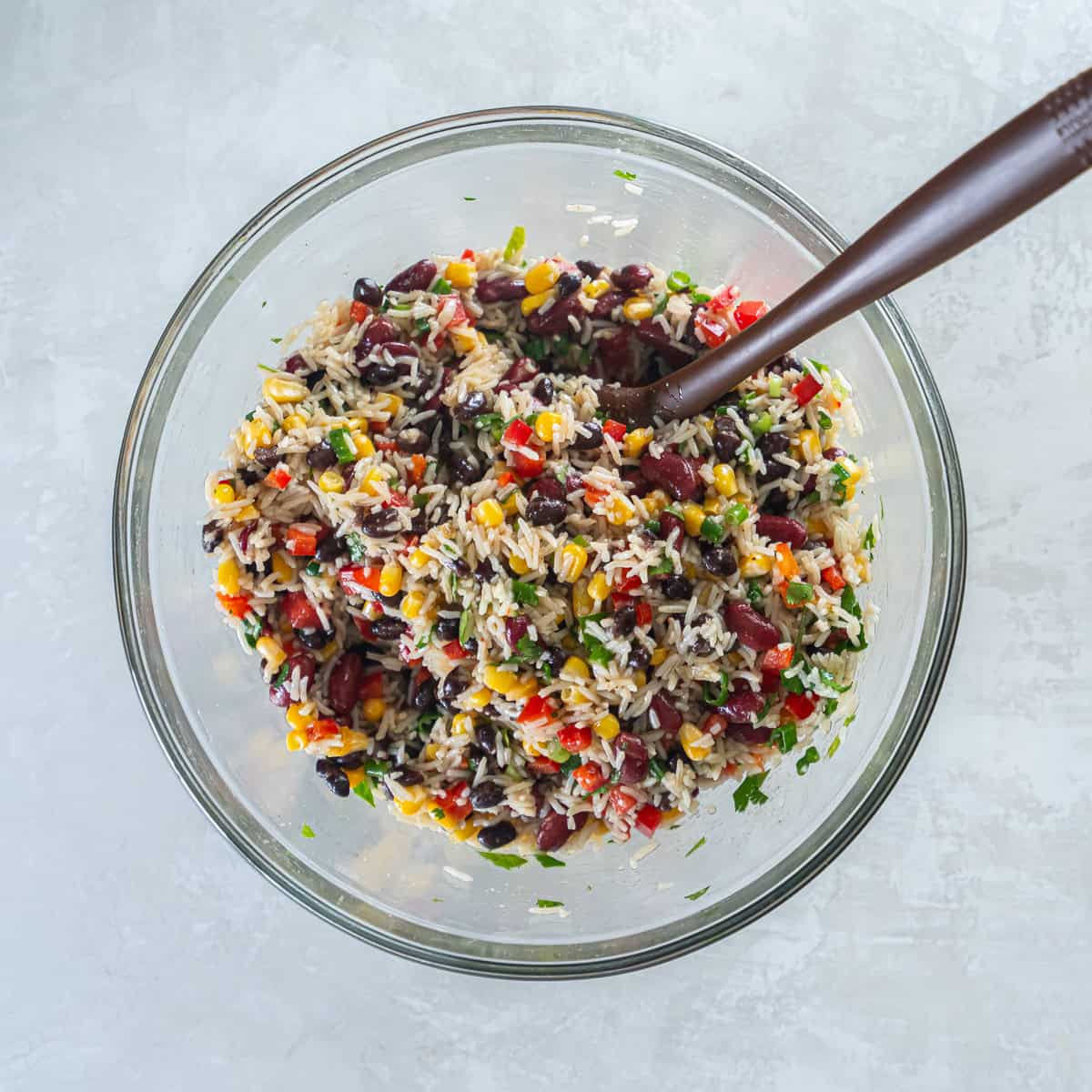 Rice and bean salad mixed with corn, black beans, kidney beans, red bell pepper, and cilantro.