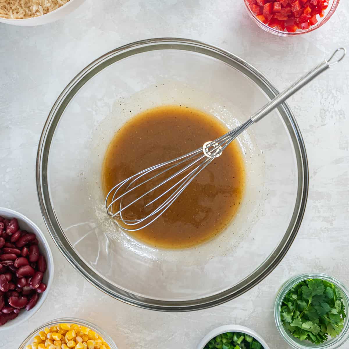 Homemade cumin-lime vinaigrette whisked together in a glass mixing bowl.