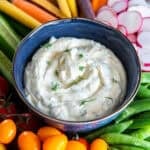 Easy vegetable dip in a bowl surrounded by fresh vegetables including carrots, snap peas, radishes, cucumbers, and cherry tomatoes.