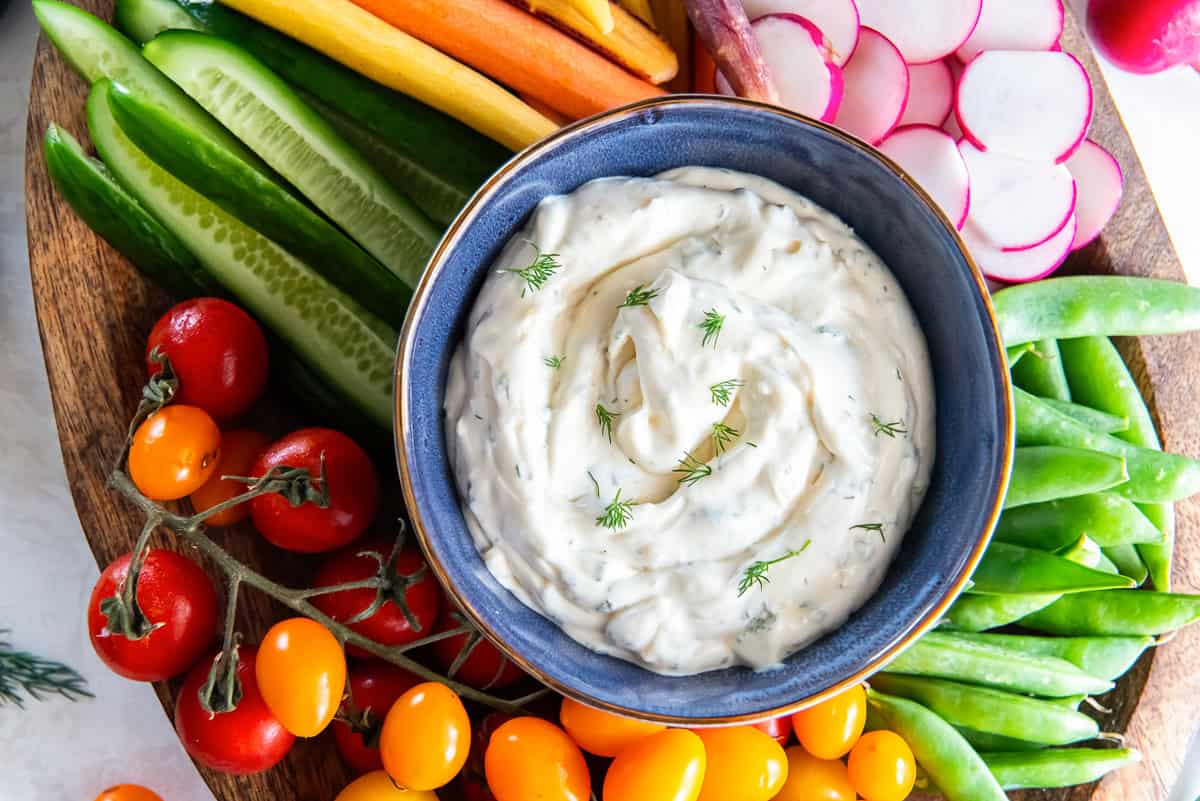 Fresh vegetables such as cucumbers, carrots, radishes, cherry tomatoes and snap peas are served with a creamy vegetable dip.