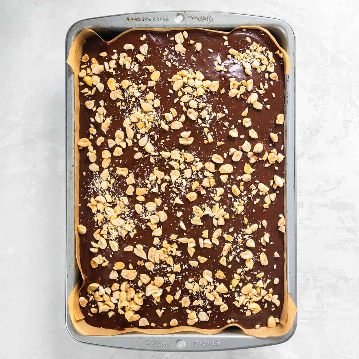 Chocolate Peanut Butter Sheet Cake topped with warm icing and chopped peanuts.