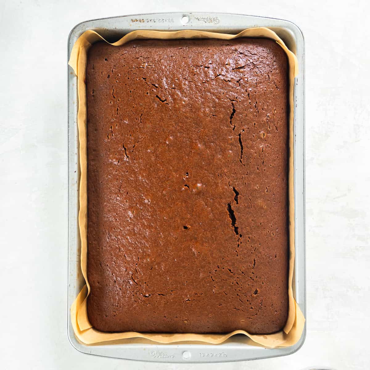 A baked peanut butter chocolate cake in a parchment-lined baking pan.