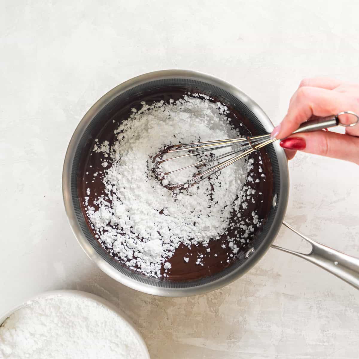 Powdered sugar being whisked into the chocolate peanut butter icing.