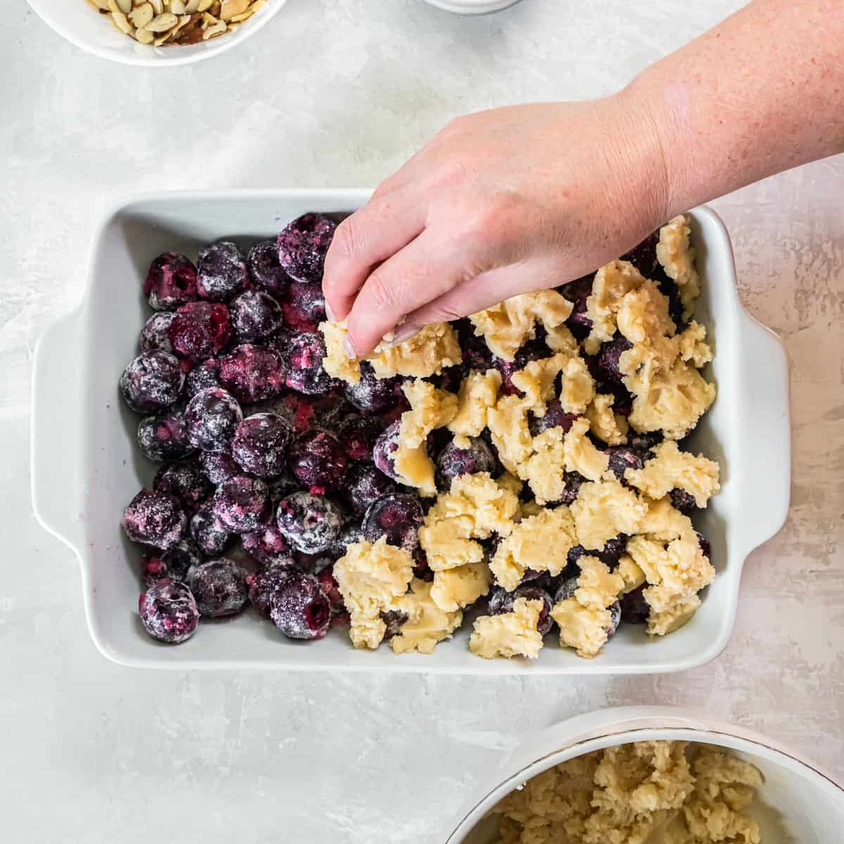 Cobbler dough scattered over fresh cherry filling in a baking dish.