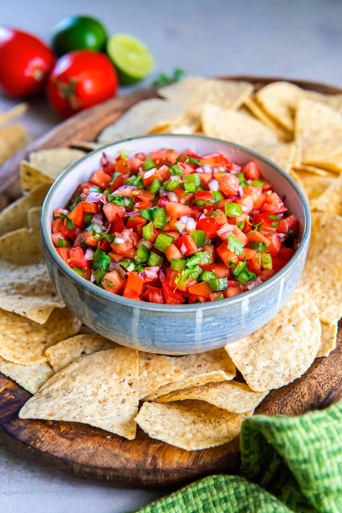 Bowl of fresh tomato salsa with tortilla chips on a wooden serving board.
