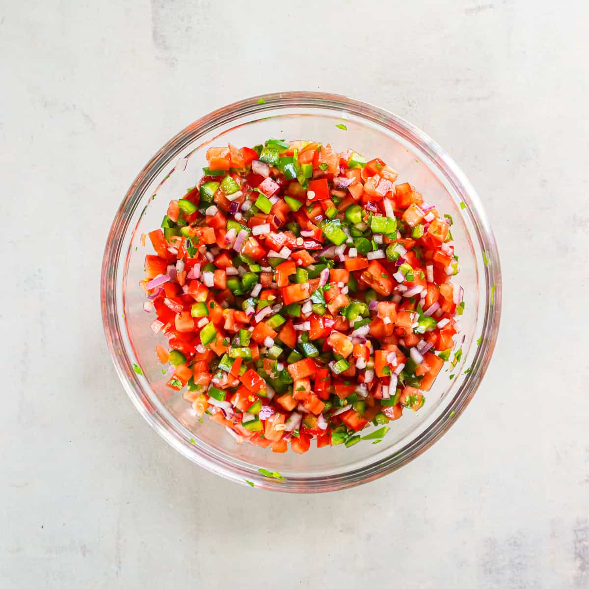 Fresh Tomato Salsa mixed together in a glass bowl with diced tomatoes, jalapeños, red onion, cilantro, and lime juice.