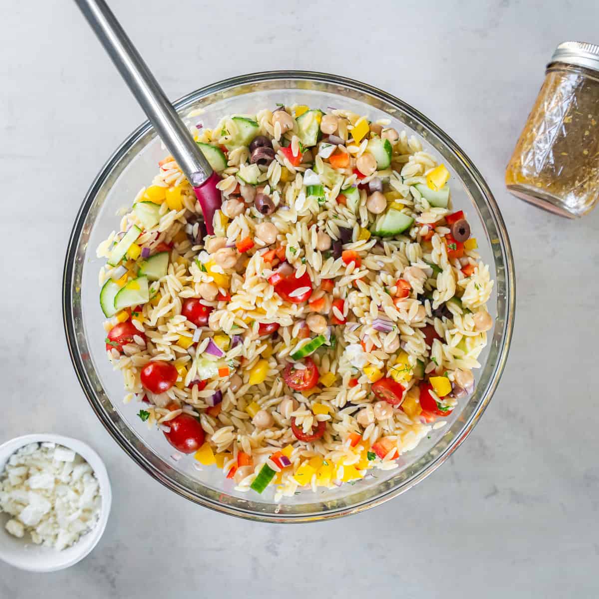 Greek orzo pasta salad in a bowl with a spoon.
